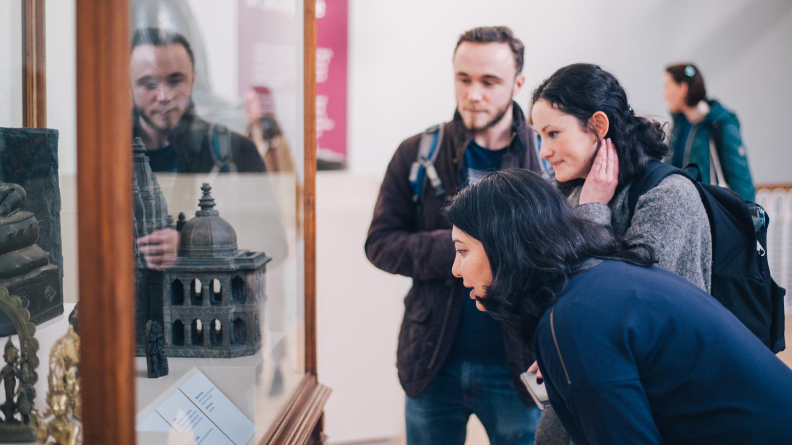 People in a museum setting looking into objects in a glass cabinet