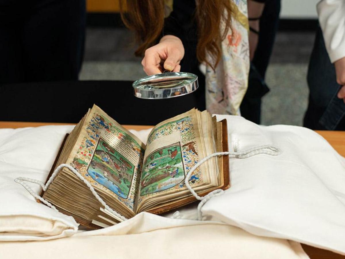 A student using a magnifying glass to look at a manuscript in the University of Edinburgh's Centre for Research Collections