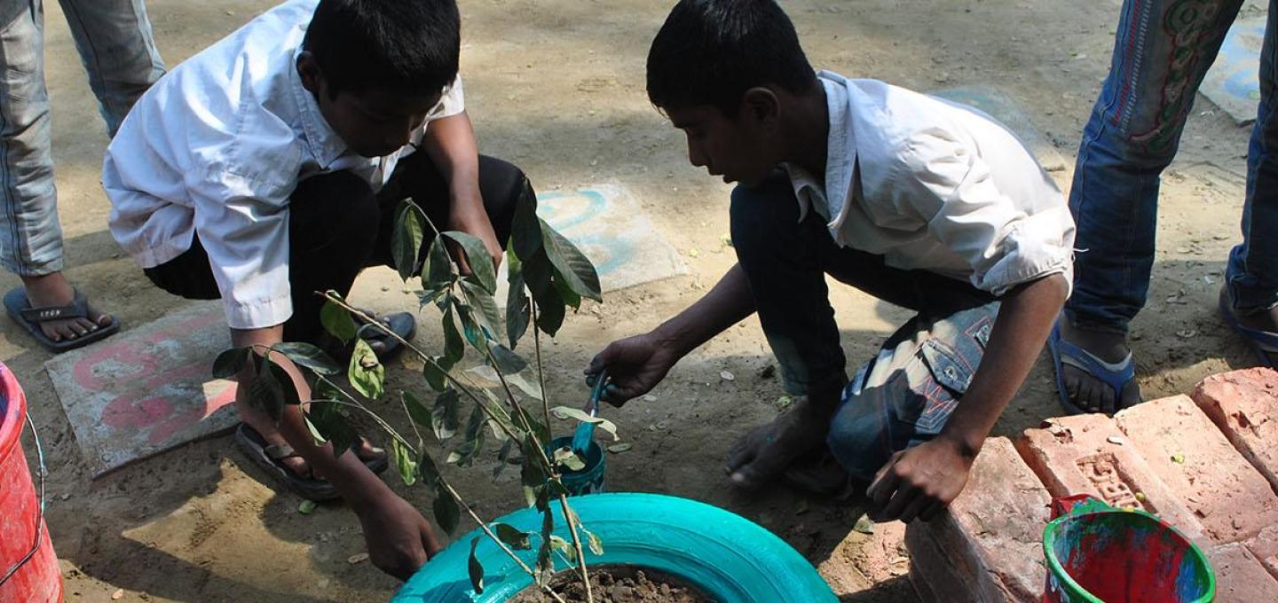 Two children painting a plant pot blue