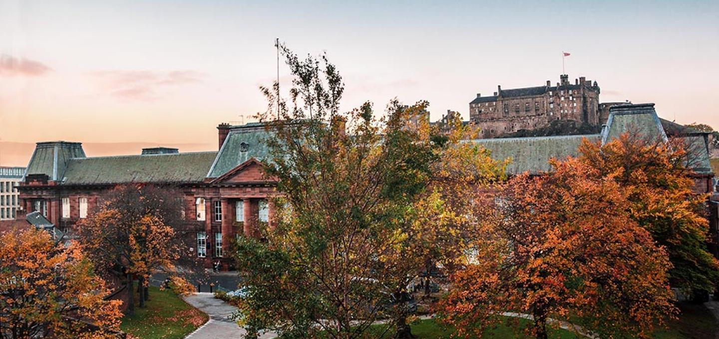 The ECA Main Building pictured at sunset on an autumn evening. Edinburgh Castle is in the background.