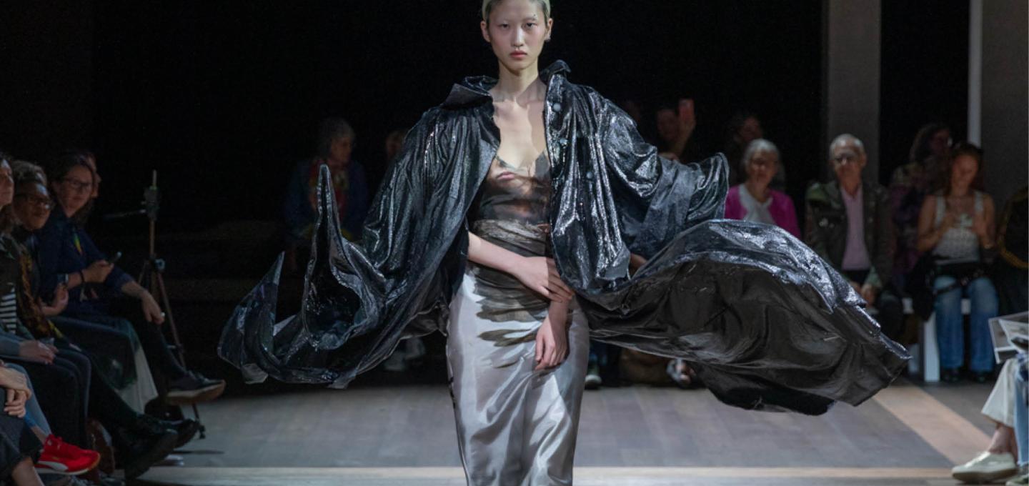 a female model walking the catwalk at the fashion graduate show, wearing a high fashion piece created by a student