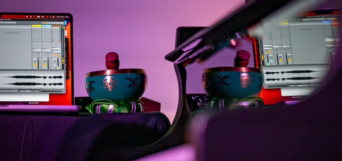 two laptops with audio editing software and two blue instruments on a desk