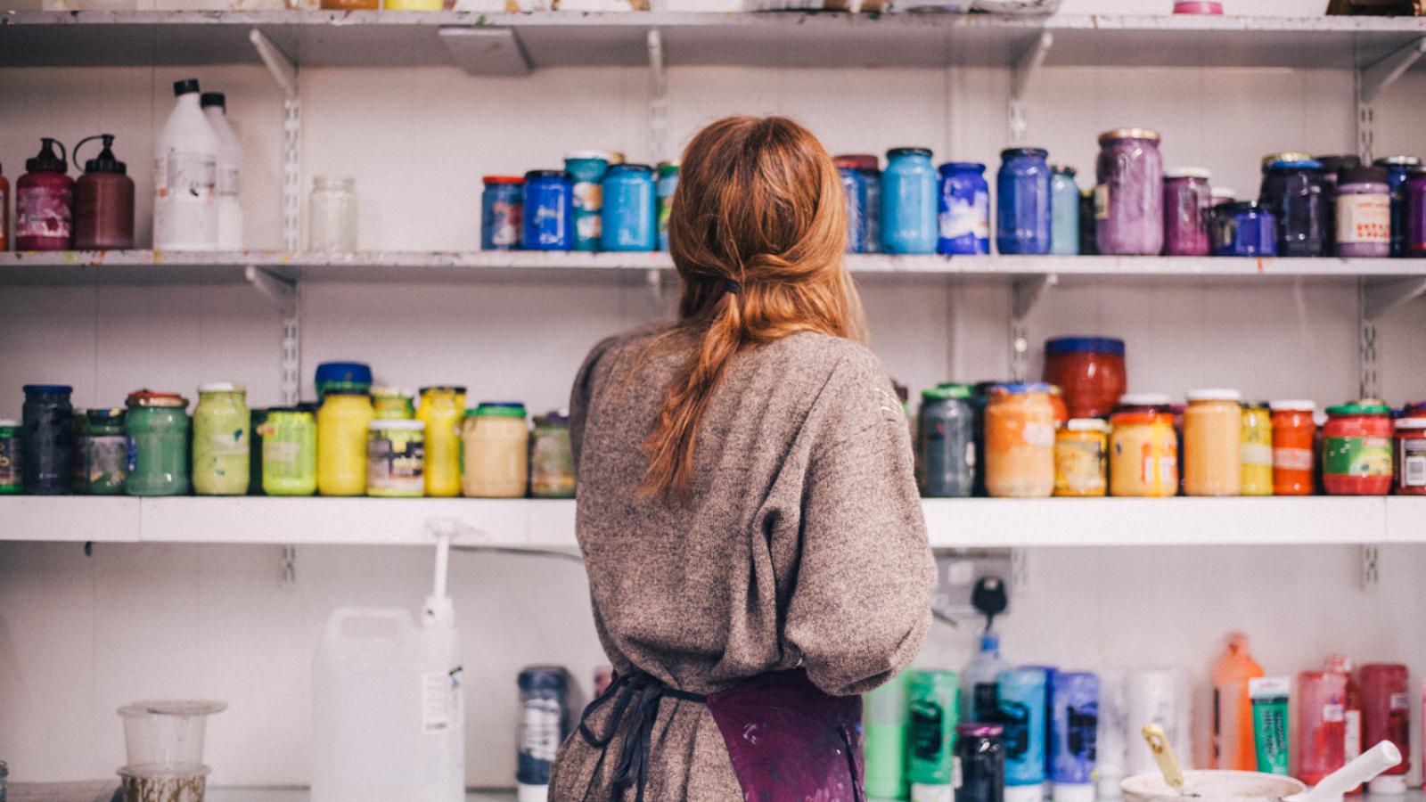 A student selecting printmaking colours from a shelf