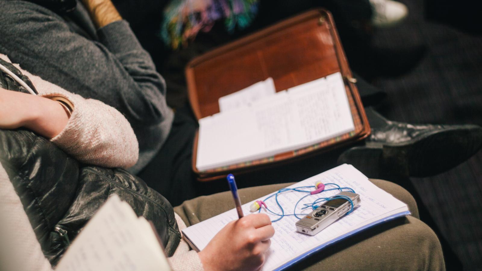 Close-up of students in a lecture, taking notes
