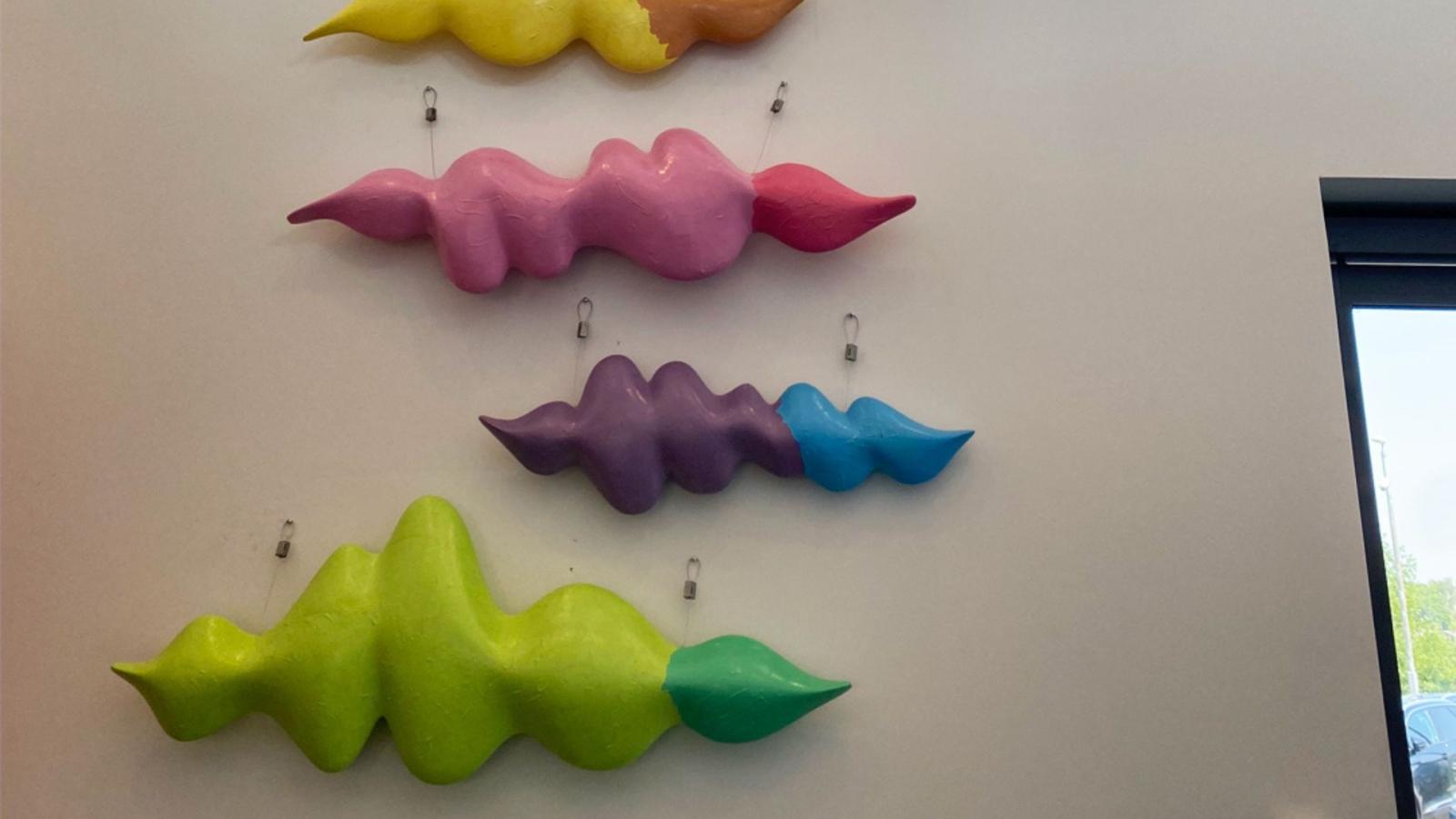 A photo of four of the colourful, soundwave-inspired artworks hanging on the wall.