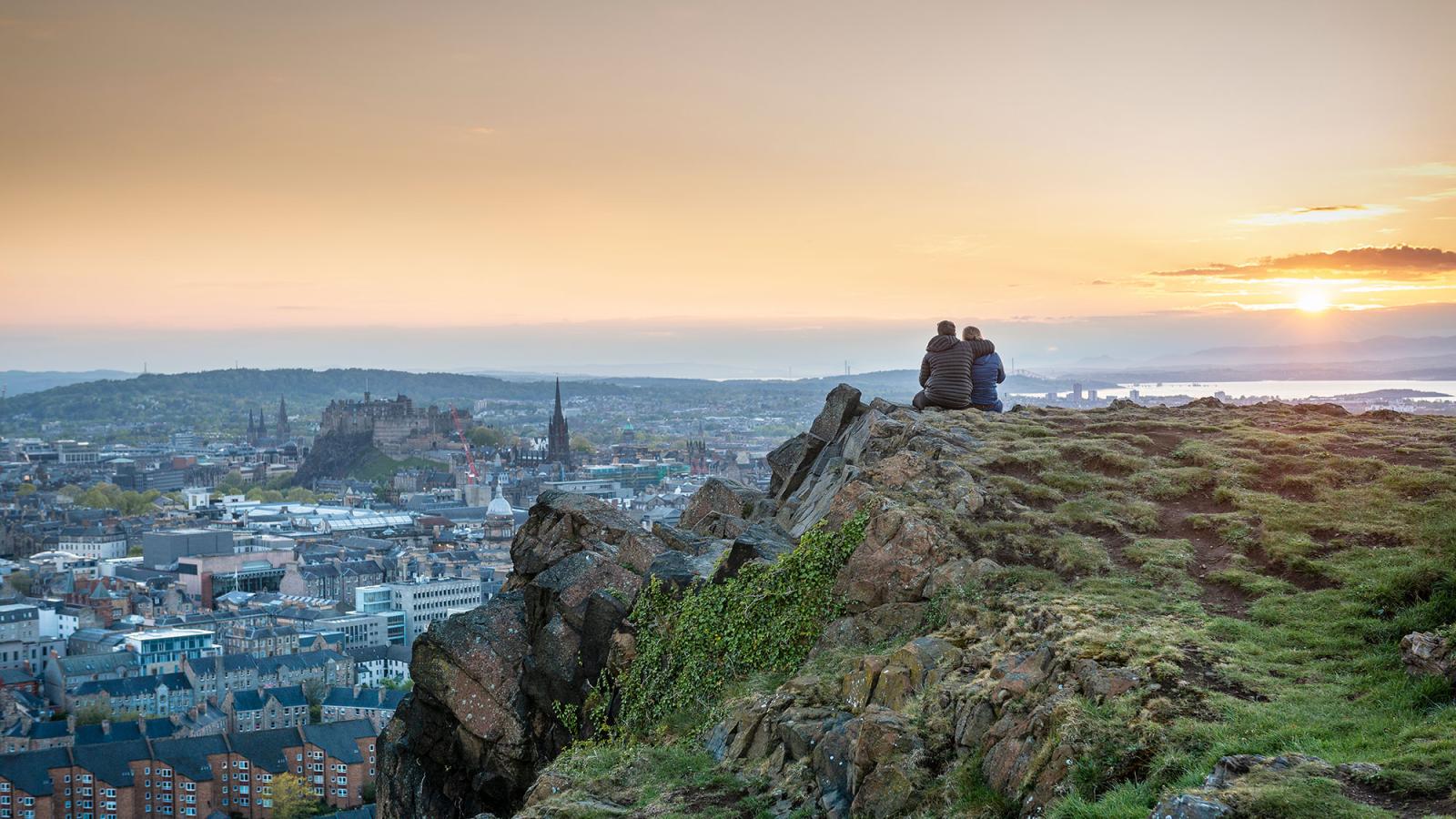 A couple sitting on the Salisbury Crags, overlooking Edinburgh