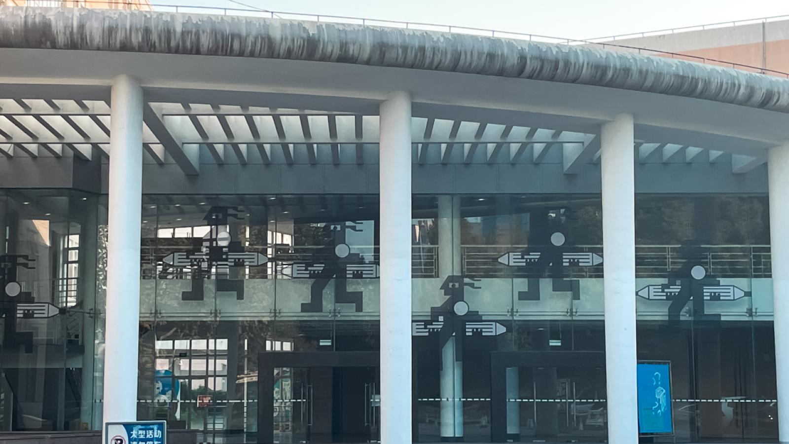 Exterior photo of SCF which shows a two-storey building with a curved facade and three columns holding up a roof incorporating glass panels.