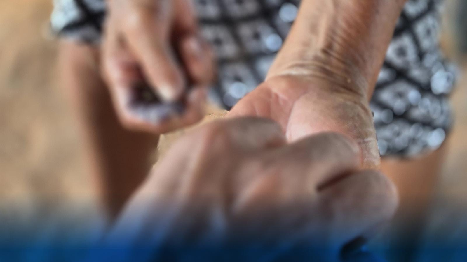 A close up of one hand placing something into another person's hand.