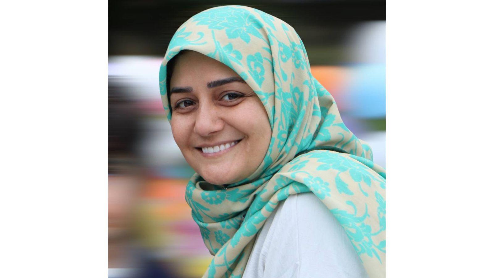 A head and shoulders photograph of Maryam Haddadi. She is pictured side on, looking left towards the camera, and smiling. She wears a white shirt, and a pale blue and cream patterned hijab.
