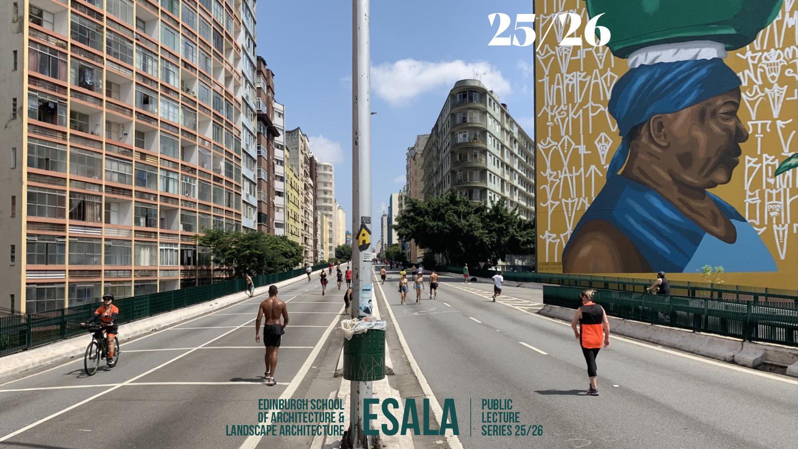 An expressway surrounded by tall buildings stretches into the distance. People walk in the middle of the road. One building on the right has a large mural of a person wearing a blue sleeveless top, a blue wrap around their head, where a green container balances.