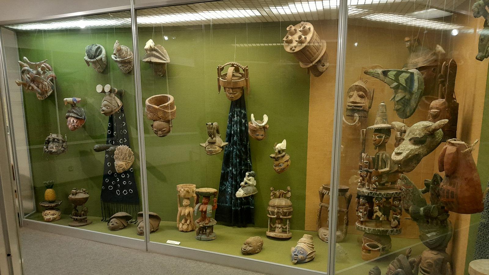 An exhibition display of different objects such as masks, statues, textiles.