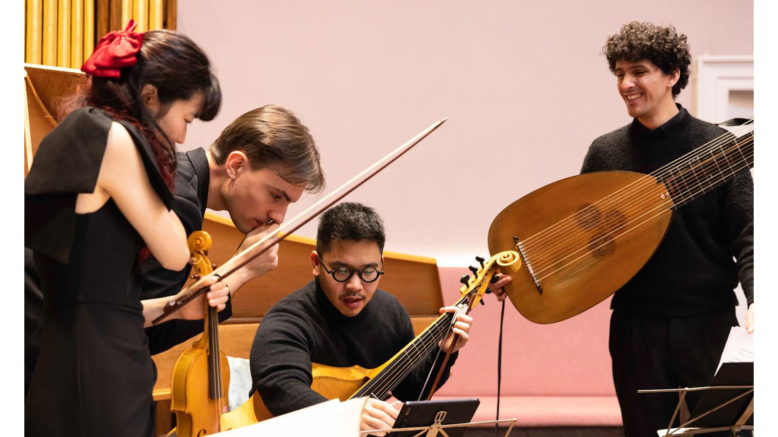 The four musicians who make up the Musica d’Outura, standing with their instruments around a music stand.