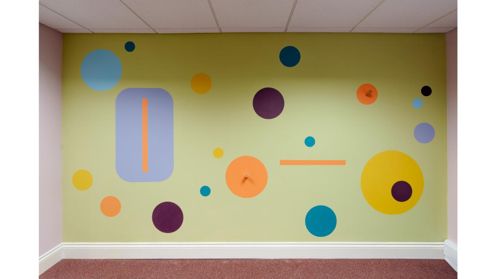 Painted rectangles and circles in a wide range of colours have been artfully painted on a wall.