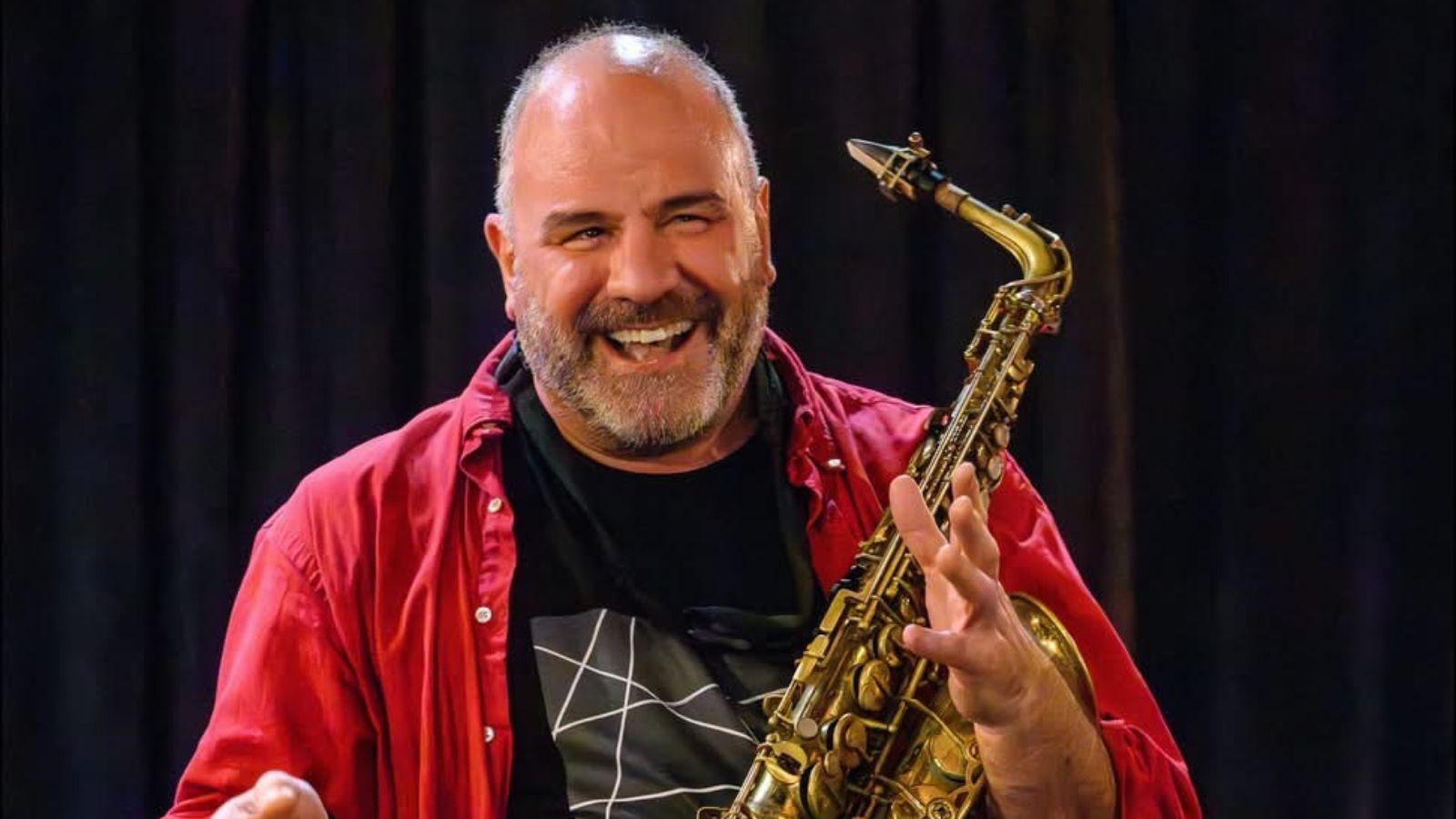 Raymond, smiling, holds his saxophone