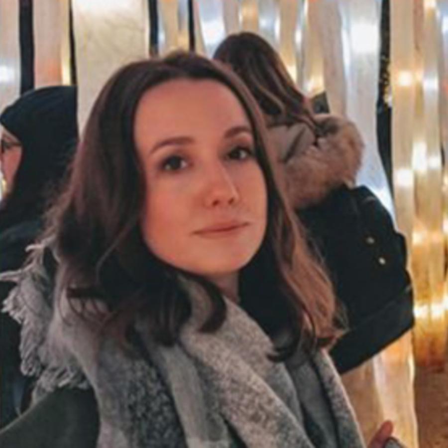 A person with short dark hair, wearing a grey and blue scarf