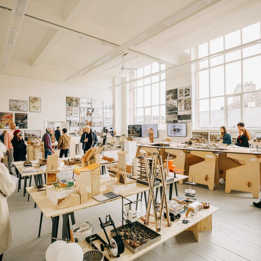 A studio space containing an exhibition of student work with people walking around it