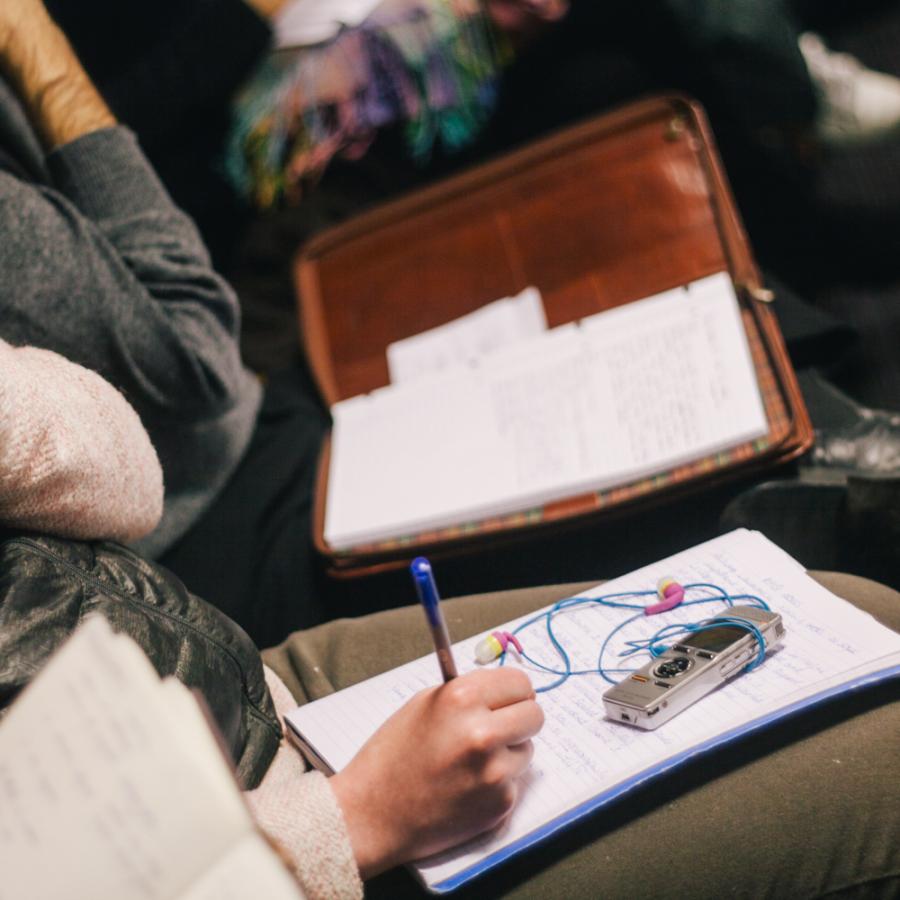 Close-up of students in a lecture, taking notes