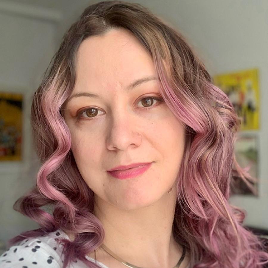 A person with long pink hair, smiling at the camera.