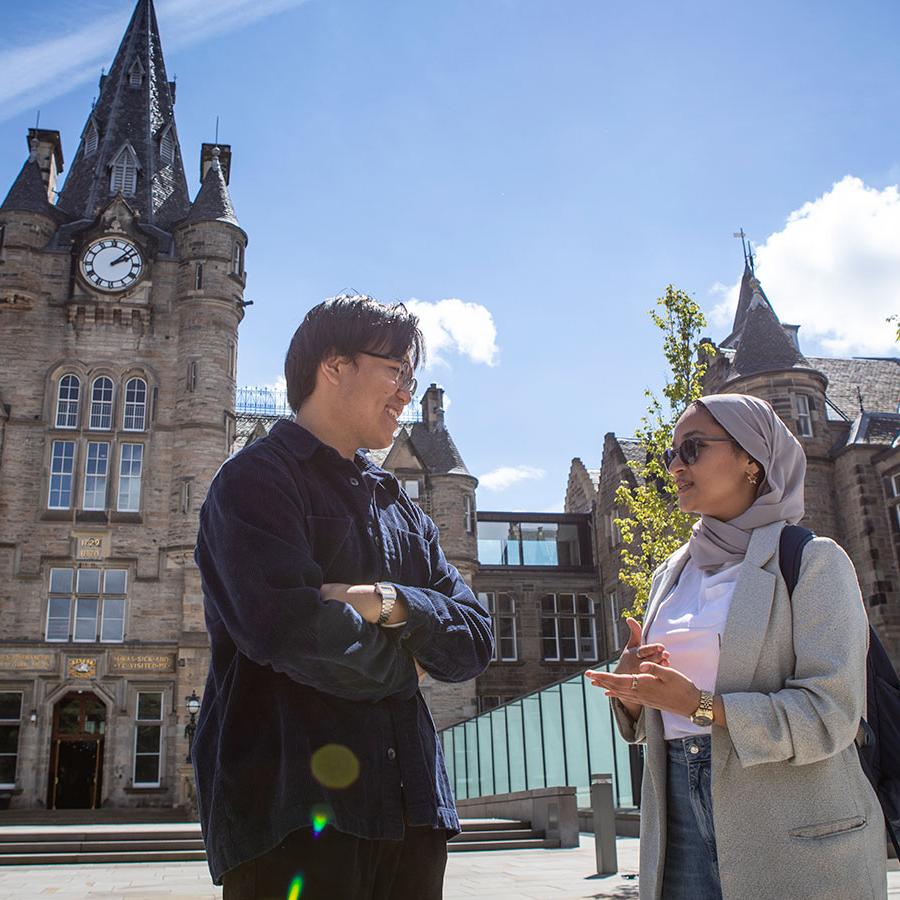 Two University of Edinburgh students stand outside the Edinburgh Futures Institute building.