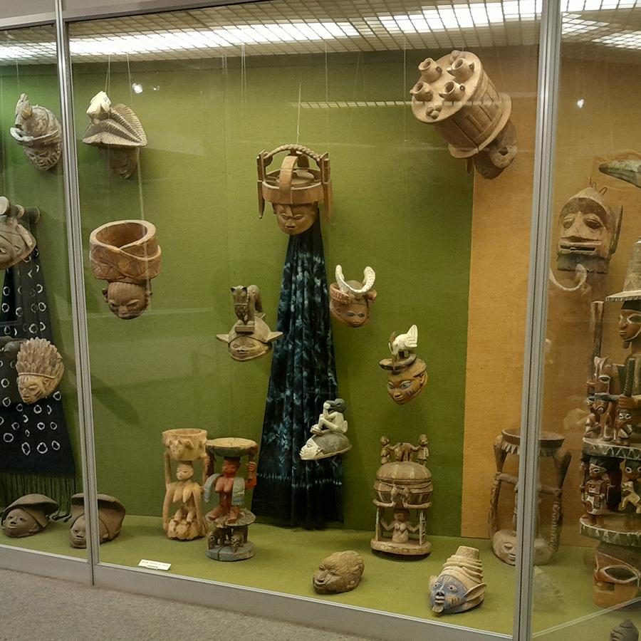 An exhibition display of different objects such as masks, statues, textiles.