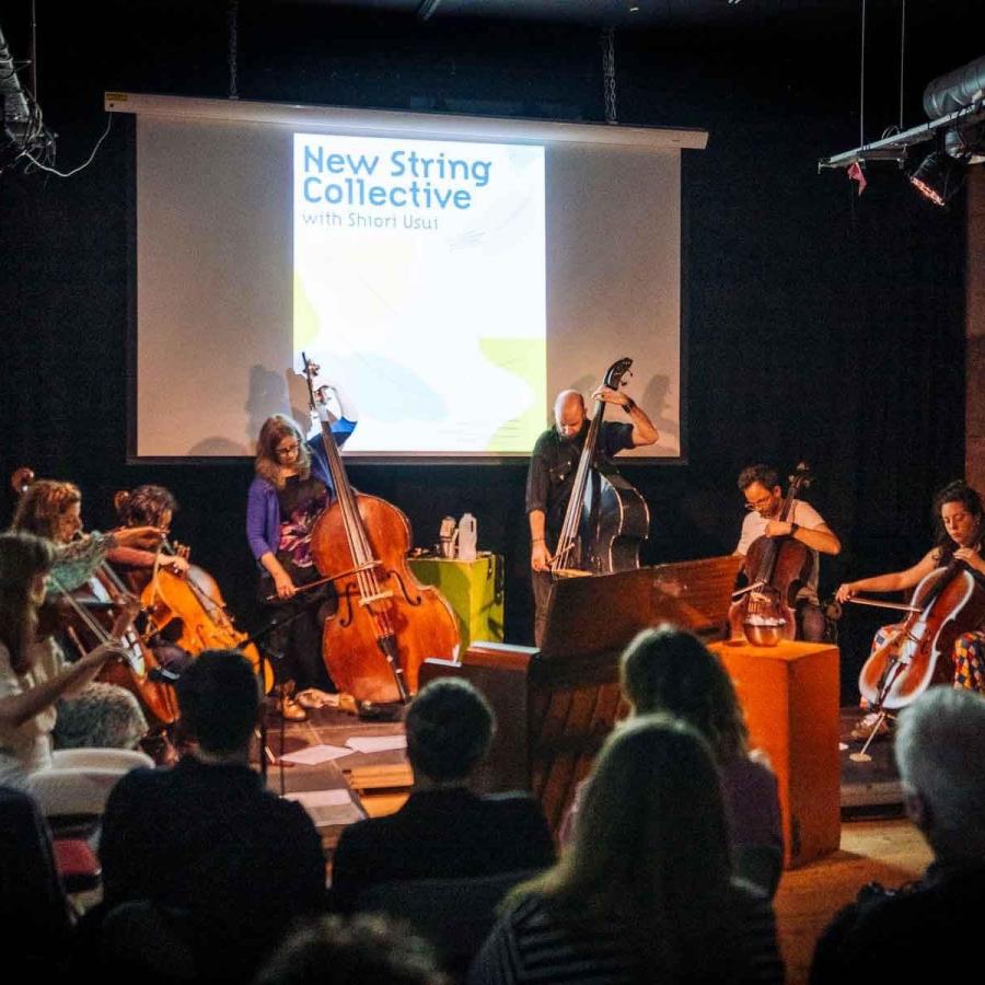 New String Collective on stage performing to a group of people.