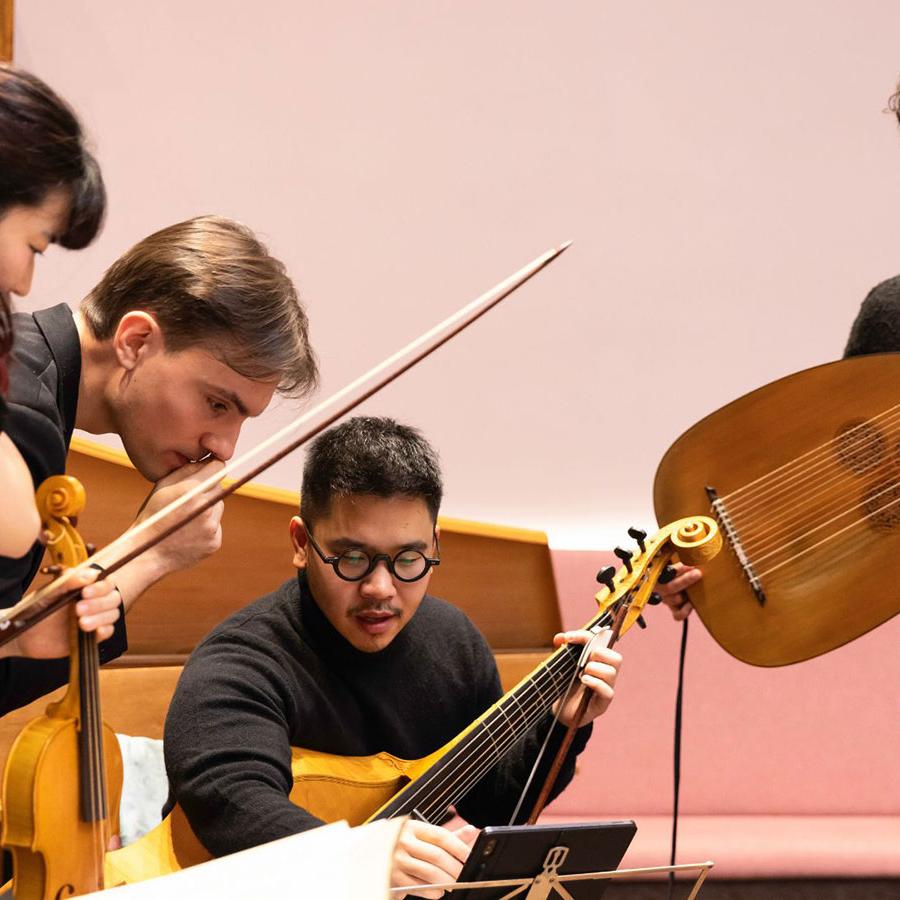 The four musicians who make up the Musica d’Outura, standing with their instruments around a music stand.
