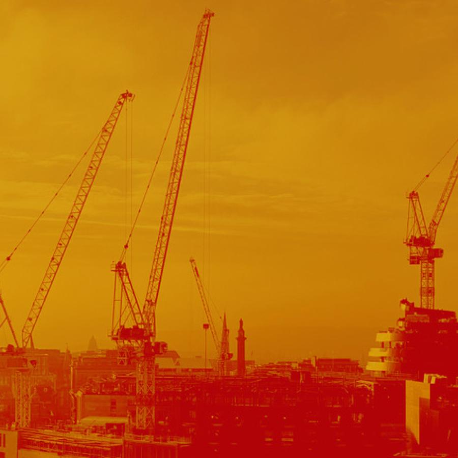 A view of the Edinburgh skyline coloured in orange and red. Four cranes and the walnut whip shape of the W hotel can be seen above the roof tops.