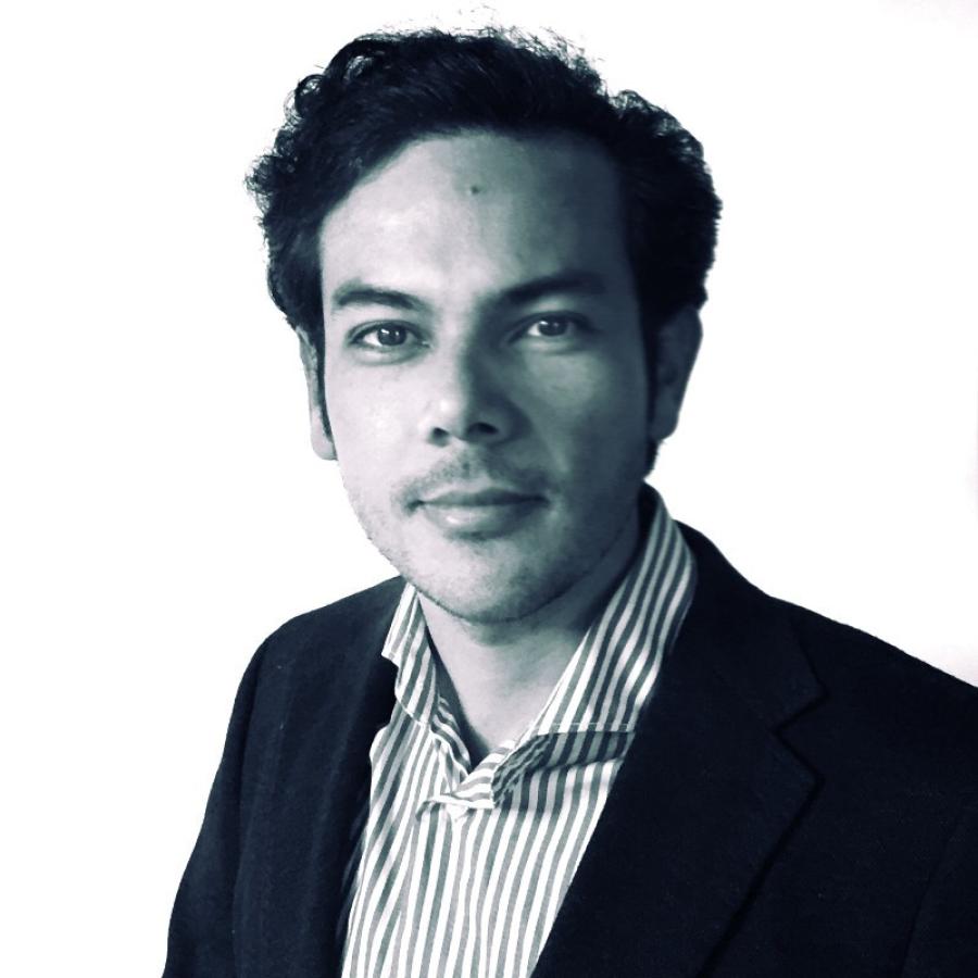 A black and white image of Edgar Gomez wearing a striped shirt and black suit jacket. He looks straight into the camera.