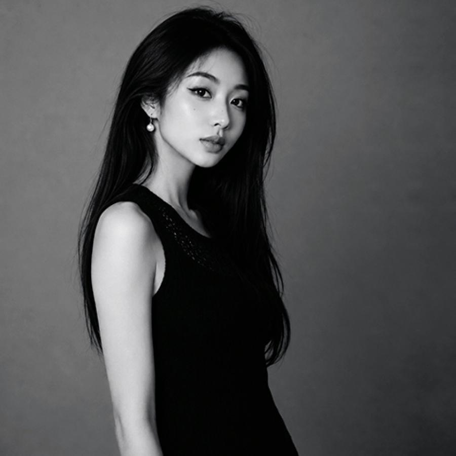 Minshu Chen has long dark hair and stands to the side but looks to the camera.