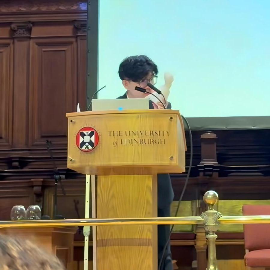 Zhiyang Ding standing behind a lecturn in the McEwan Hall.