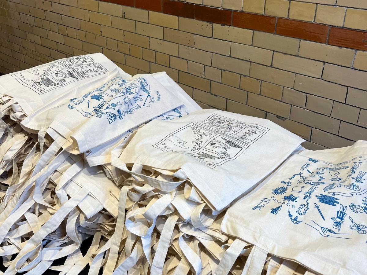 A photo of illustrated tote bags on a table at a graduation reception.