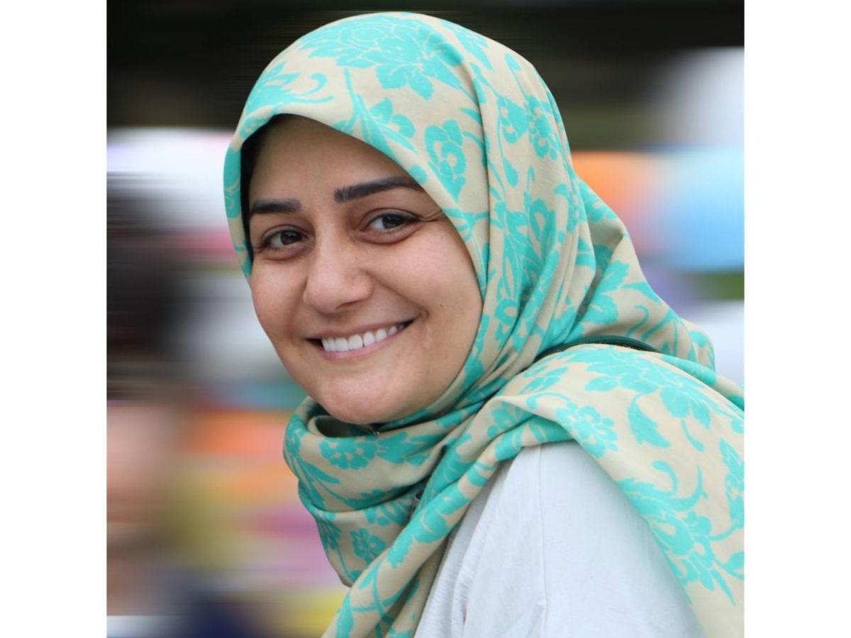 A head and shoulders photograph of Maryam Haddadi. She is pictured side on, looking left towards the camera, and smiling. She wears a white shirt, and a pale blue and cream patterned hijab.