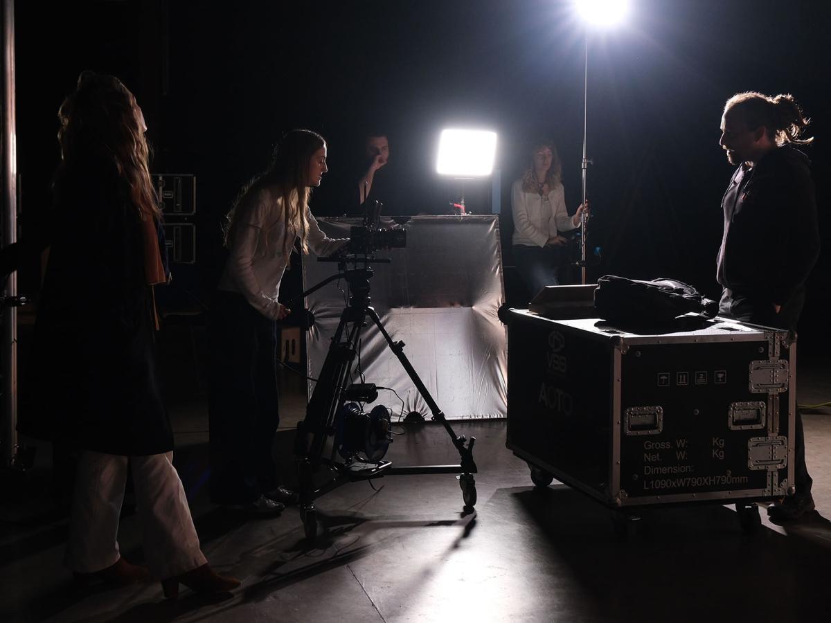 A student is looking through a camera lens.