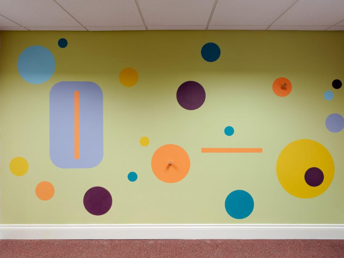 Painted rectangles and circles in a wide range of colours have been artfully painted on a wall.