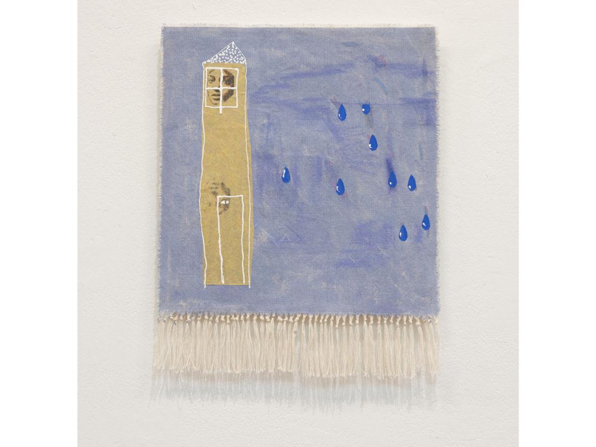 A canvas with knotted tassels at the bottom. The canvas is painted a textured, pale blue, with several large drops in a darker blue. There is a tall, thin, sandy-coloured tower with a large face appearing in a window at the top. 