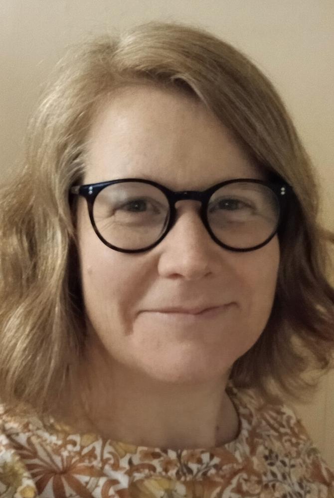 Photo of Michelle Bastian, with mid length auburn hair, dark glasses. 