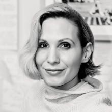 A black and white photo of a person with short hair swept to the side, and a roll neck jumper on.