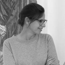 A black and white image of a person looking sideways, wearing glasses and a plain jumper.