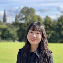 A person with dark hair, sitting in a park in Edinburgh