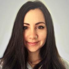 A person with long dark hair, smiling at the camera