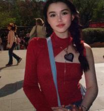 Chuan Jiang outside, wearing a red top with a cut out on one shoulder.