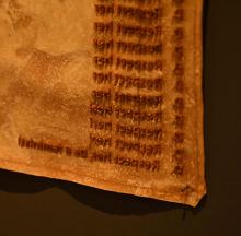 A piece of yellow/orange fabric with embossed writing upon it.