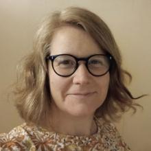 Photo of Michelle Bastian, with mid length auburn hair, dark glasses. 