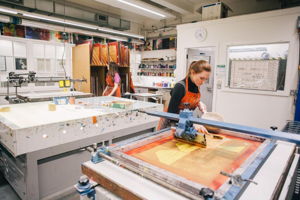 Students working with equipment in the printmaking studio