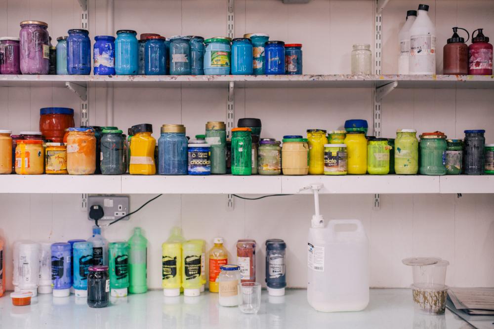 Shelves containing different colours of paints and inks