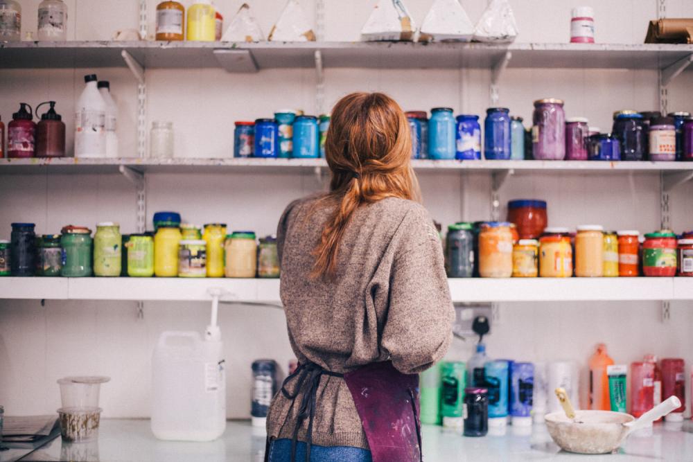 A student selecting printmaking colours from a shelf