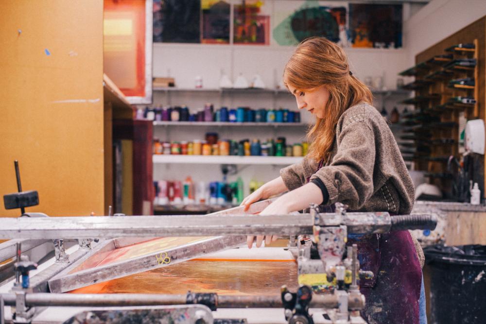 A student working with equipment in the printmaking studio