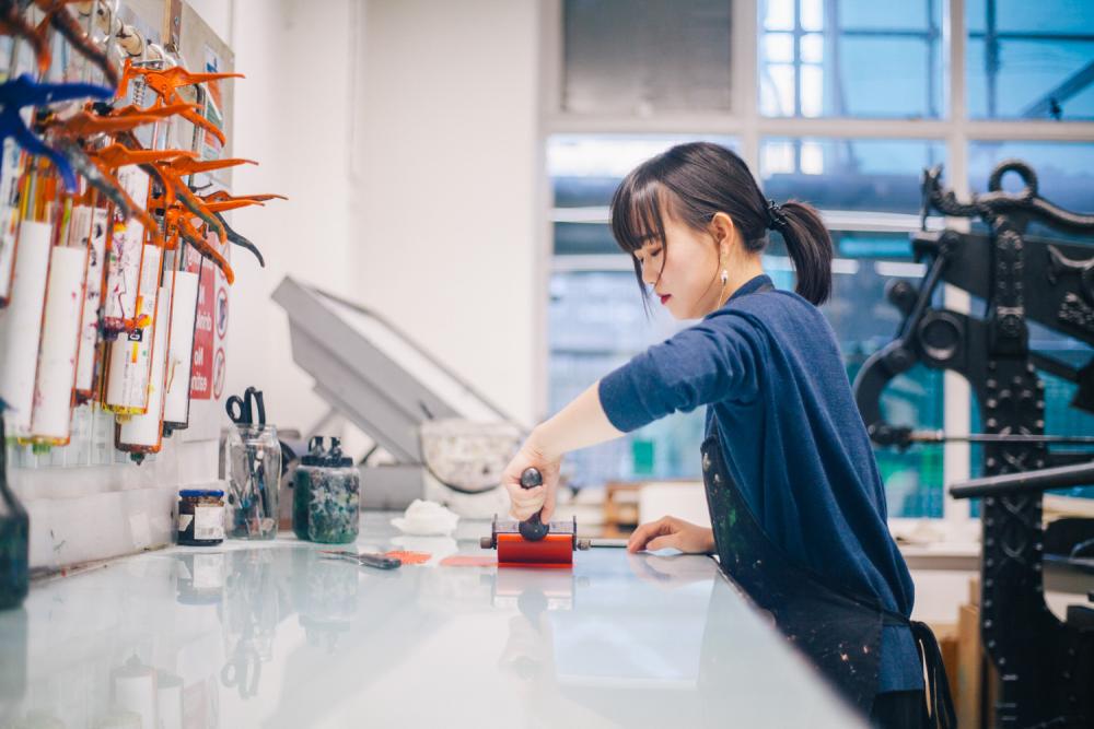A student working with equipment in the printmaking studio