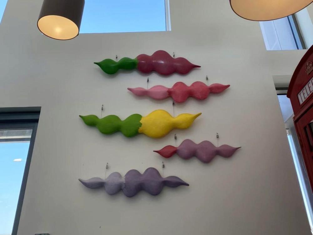 A photo of five pieces of the colourful, soundwave-inspired artwork on the wall of the care home.