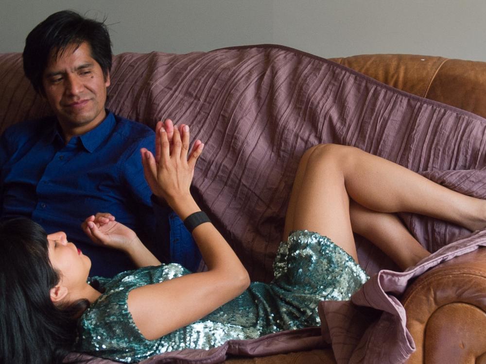 Two people on a sofa, one sitting with the other lying across them.